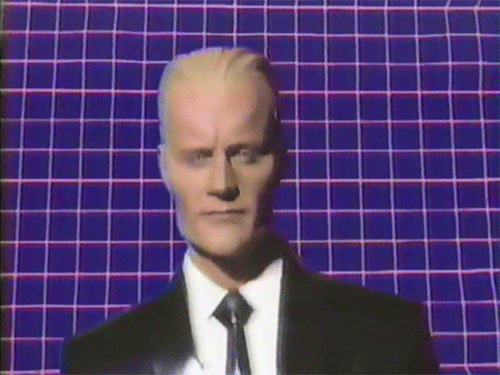animated image of Max Headroom bobbing his head side to side as if dancing. The background is a grid that becomes distorted and returns