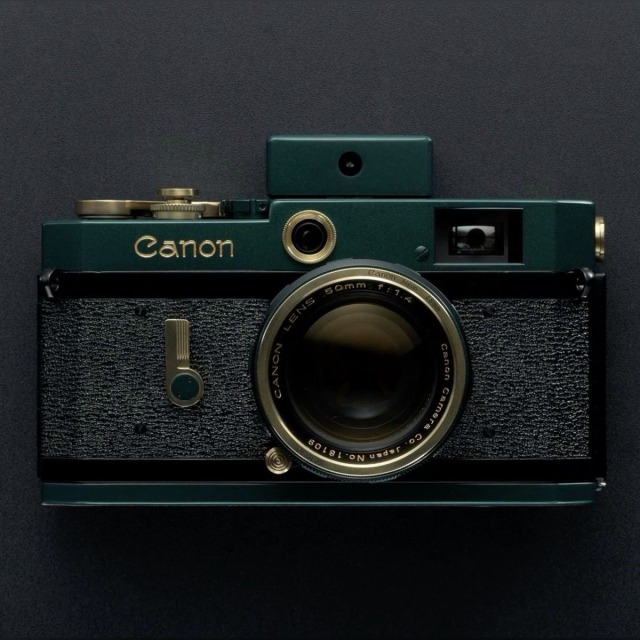 A vintage Canon rangefinder camera in deep forest green and textured black leather, featuring brass accents, a gold-etched Canon logo, and a 50mm f/1.4 lens.